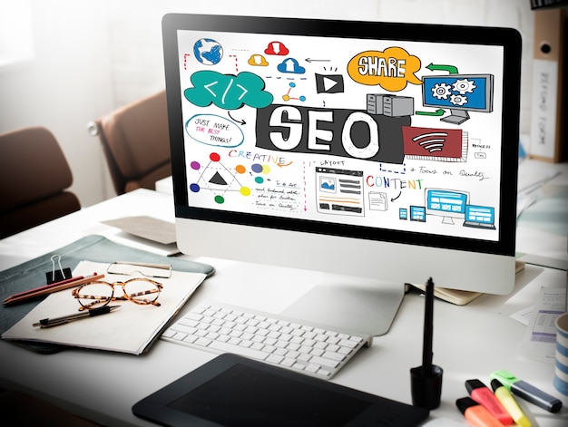 Desktop screen showing SEO concepts with icons and charts on a cluttered desk.