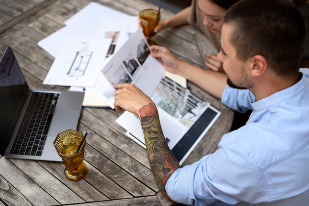 Designers reviewing architectural plans at outdoor table.