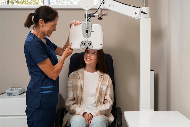 An eye care professional adjusts a diagnostic device while the patient smiles during a follow-up vision exam in the clinic.
