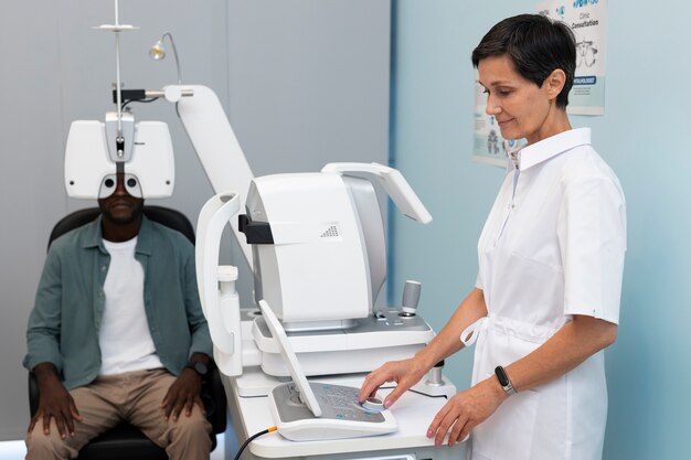 Eye doctor using digital vision testing equipment as a patient undergoes an eye exam with a phoropter in a clinic.